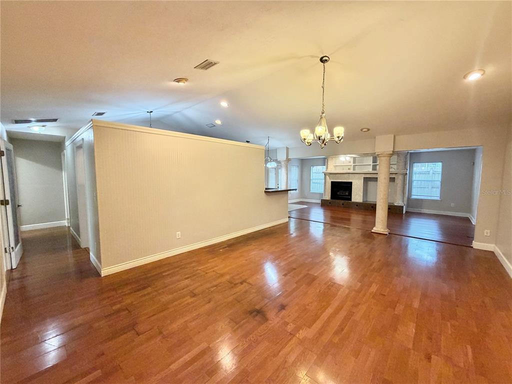 A living area with hardwood floors, a half-wall partition, and a fireplace with columns — 11512 NW 13TH LANE, GAINESVILLE, FL