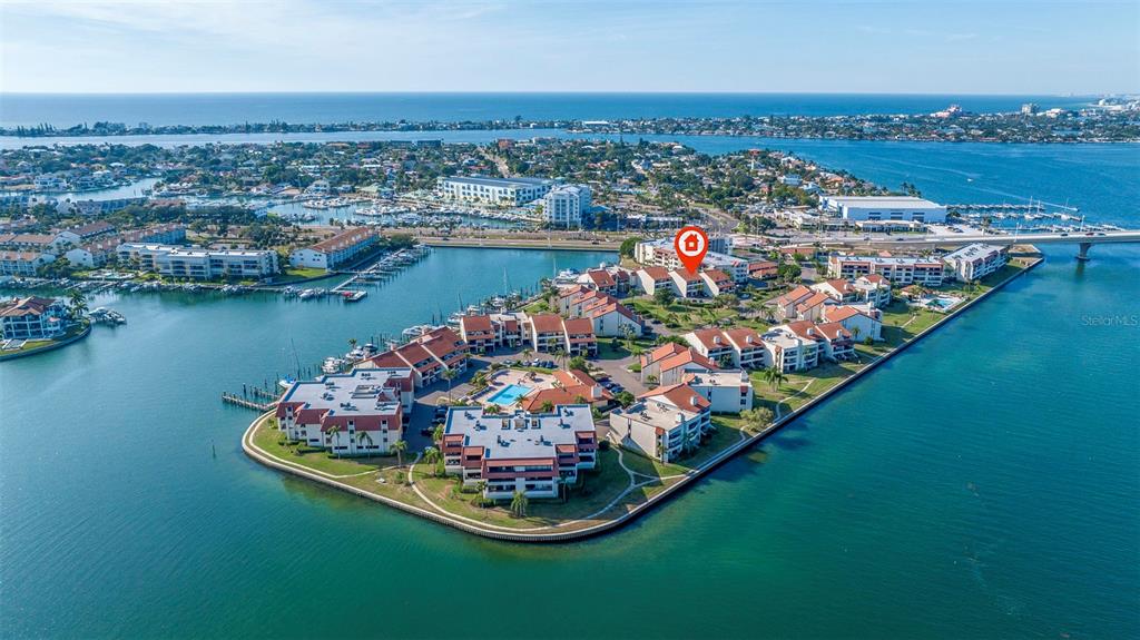 An aerial view shows a waterfront condominium complex surrounded by water on three sides — 120 1ST STREET E UNIT 108, TIERRA VERDE, FL
