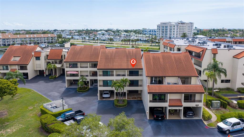 An aerial view of a multi-story residential complex with terracotta roofs and covered parking — 120 1ST STREET E UNIT 108, TIERRA VERDE, FL