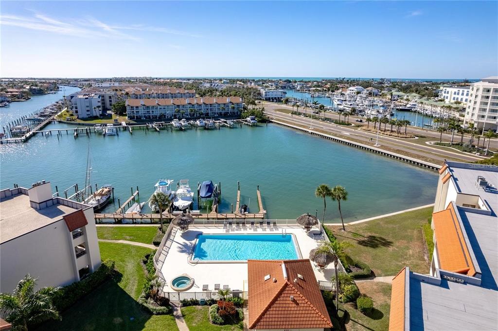 An aerial view shows a swimming pool, boat docks, and a waterway near the coast — 120 1ST STREET E UNIT 108, TIERRA VERDE, FL