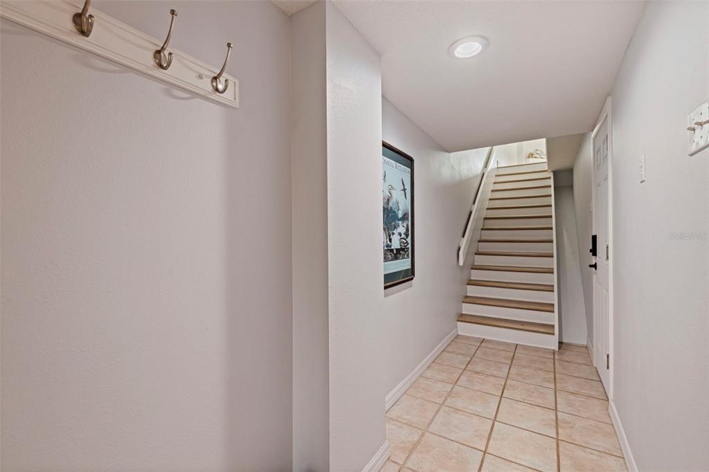 An entryway with tile flooring, a coat rack, and stairs leading to an upper level — 120 1ST STREET E UNIT 108, TIERRA VERDE, FL