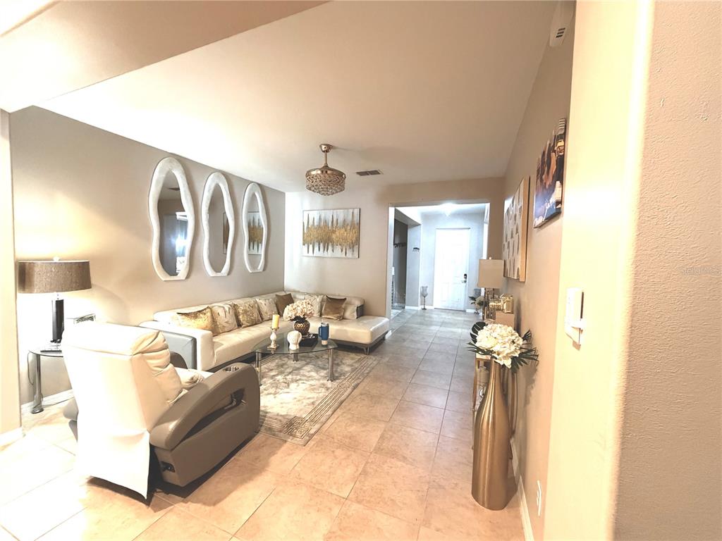 A living room features a white sectional sofa, a recliner, and three oval wall mirrors — 3982 BLOSSOM DEW DRIVE, KISSIMMEE, FL