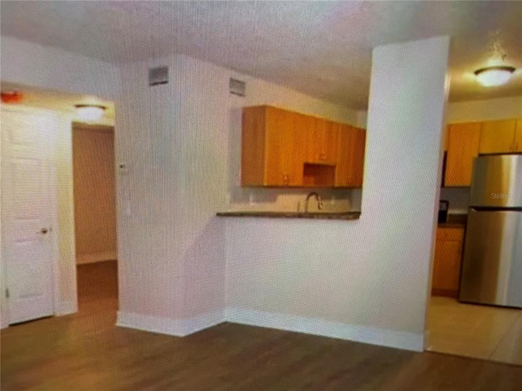 A view of a kitchen with light wood cabinets and a breakfast bar from a living area — 21038 VOYAGER BOULEVARD UNIT 4, LAND O LAKES, FL