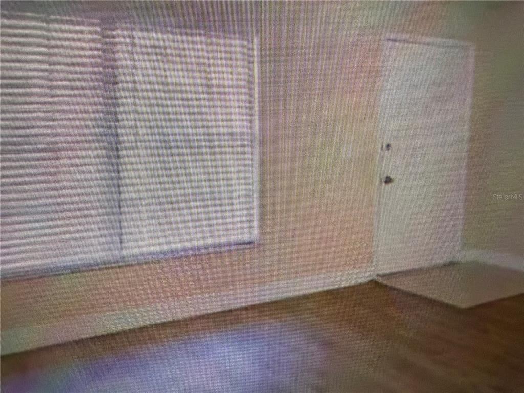 An interior room features light-colored walls, wood-look flooring, a window with blinds, and a door — 21038 VOYAGER BOULEVARD UNIT 4, LAND O LAKES, FL