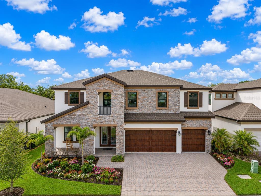 A patio with wooden chairs and a table overlooks a swimming pool and wooded area — 13113 WILDFLOWER MEADOW DRIVE, RIVERVIEW, FL