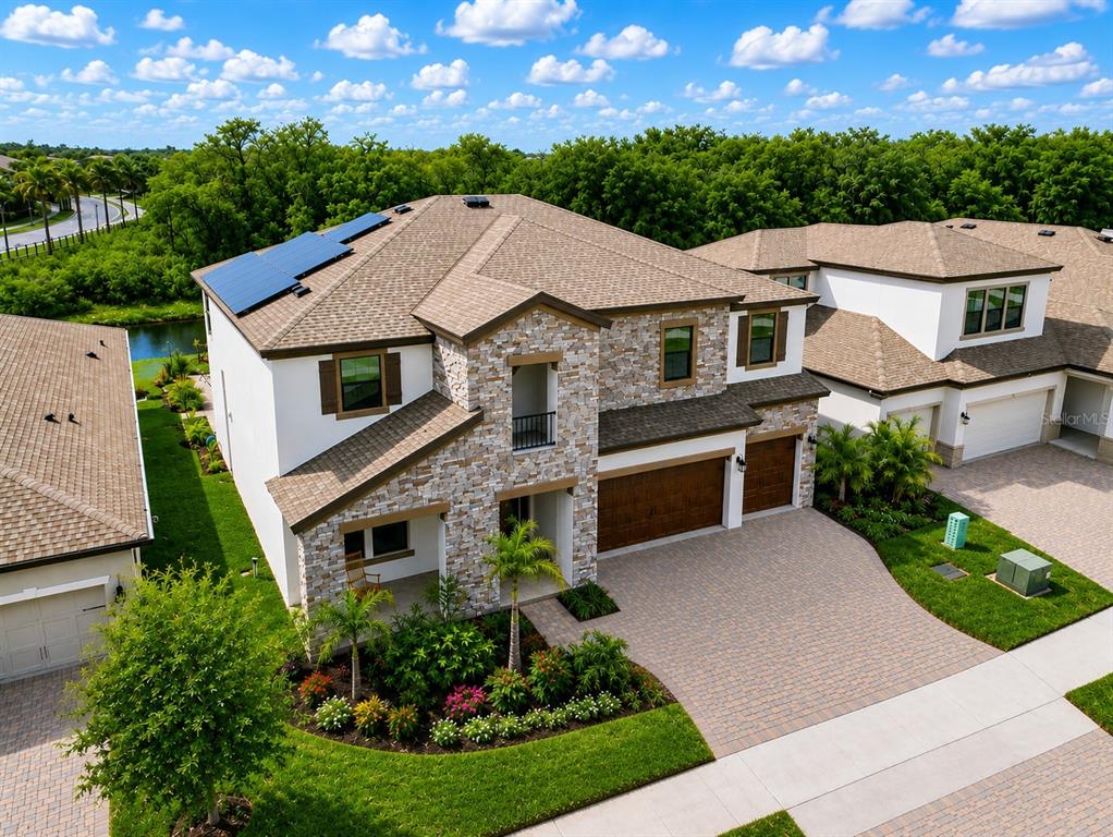 A two-story suburban house features a stone facade, a paved driveway, and a three-car garage — 13113 WILDFLOWER MEADOW DRIVE, RIVERVIEW, FL