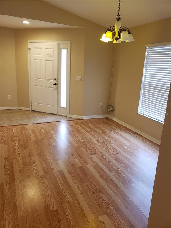 An entryway with tile flooring leads into a dining area featuring hardwood floors and chandelier — 31316 TRIBOROUGH DRIVE, WESLEY CHAPEL, FL