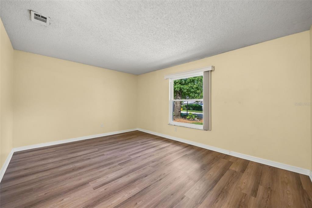 An empty bedroom features light yellow walls, wood-look flooring, and a single window — 2808 TAMARACK TRAIL, APOPKA, FL