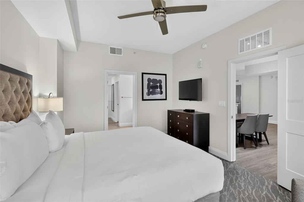 A bedroom features a king bed, dark wood dresser, ceiling fan, and an adjacent dining area — 14501 GROVE RESORT AVENUE UNIT 3438, WINTER GARDEN, FL