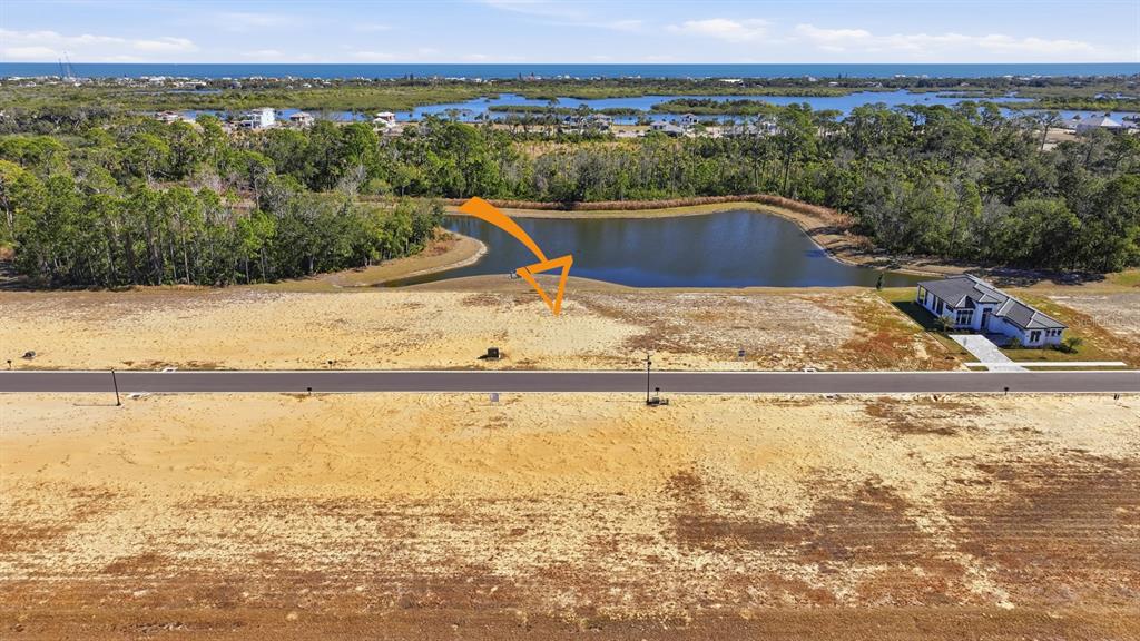 An aerial view shows a vacant, sandy residential lot bordering a pond and a paved road — 200 STILLWATER DRIVE, FLAGLER BEACH, FL