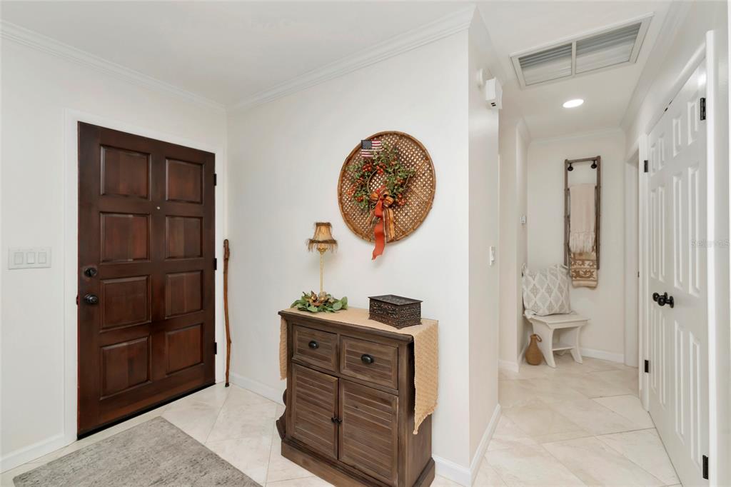 An entryway features a dark wood door, a wooden cabinet, and a small seating area — 3602 JOYCE DRIVE, BRADENTON, FL
