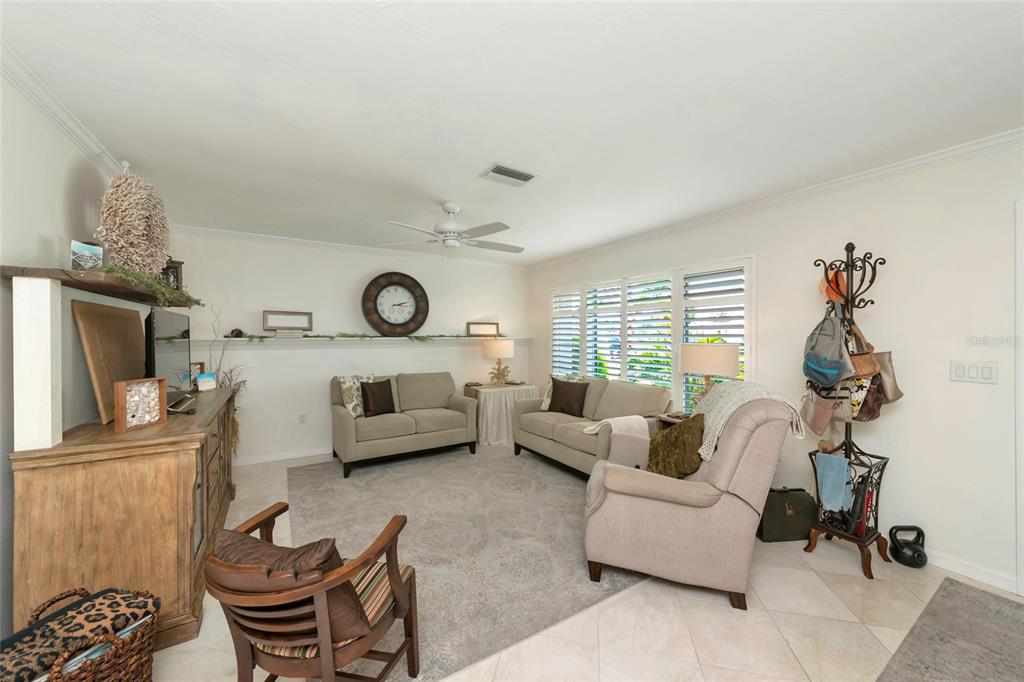 A living room features two beige sofas, an armchair, a wooden console, and a wall shelf — 3602 JOYCE DRIVE, BRADENTON, FL