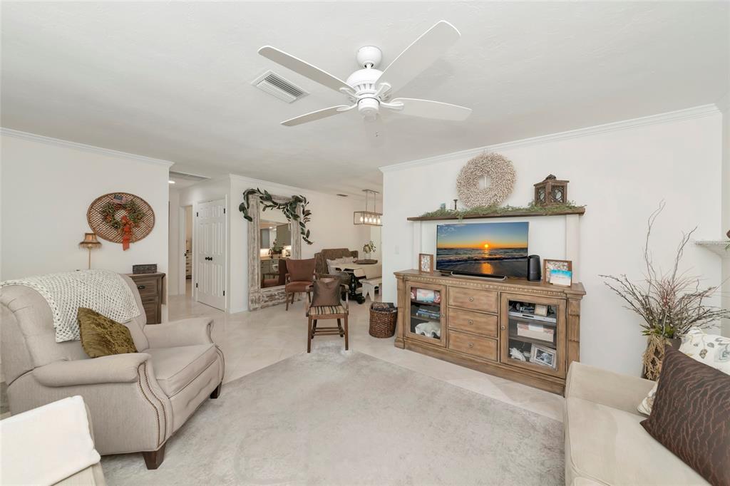A living room features a ceiling fan, a wooden media console, and neutral-toned furniture — 3602 JOYCE DRIVE, BRADENTON, FL