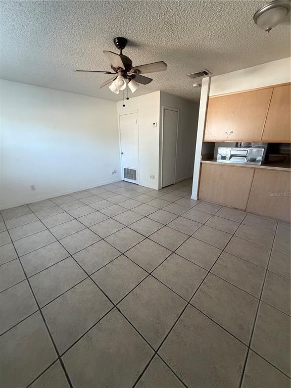 A room with light-colored tile flooring, a ceiling fan, and wooden kitchen cabinetry — 1 LAKE VILLA WAY, KISSIMMEE, FL