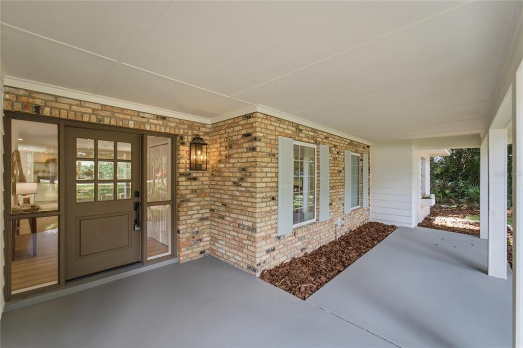 A covered brick porch features a brown front door with glass panels and gray shutters — 114 WAYLAND CIRCLE, LONGWOOD, FL