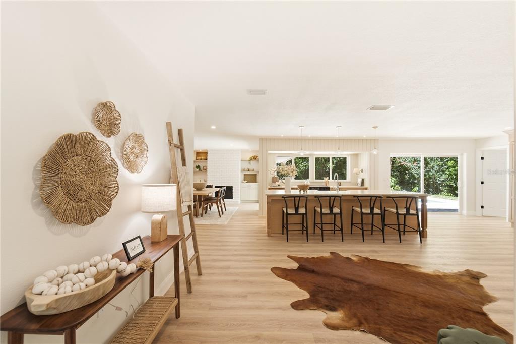 An open-concept kitchen and living area features light wood flooring, a large island, and decor — 114 WAYLAND CIRCLE, LONGWOOD, FL