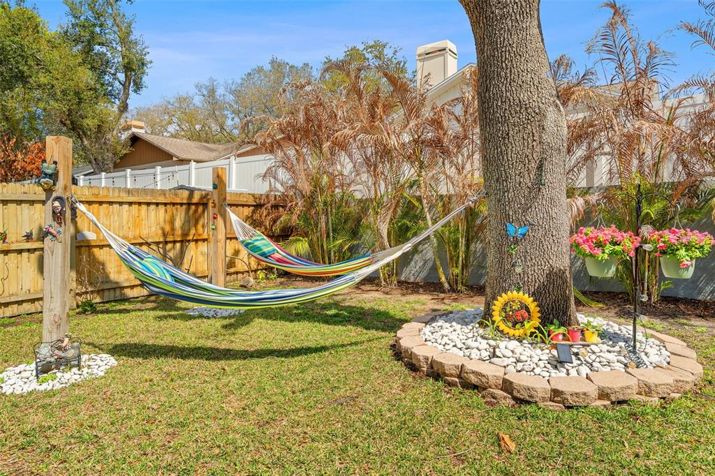 A backyard features a hammock strung between a wooden post and a large tree — 2715 BERRYKNOLL PLACE, VALRICO, FL