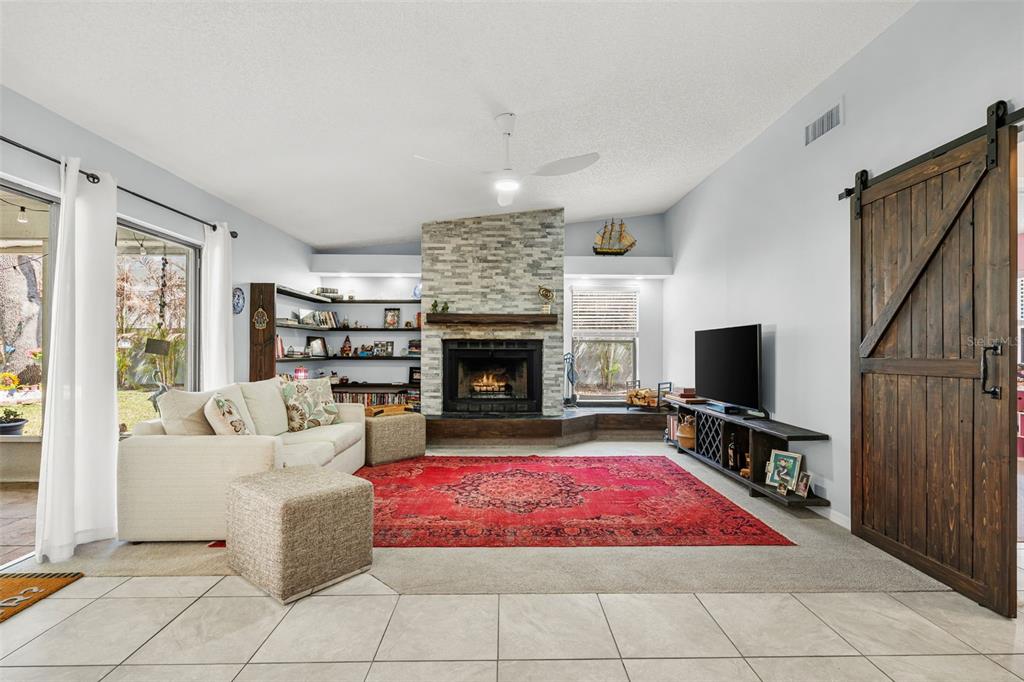A living room features a stone fireplace, a red area rug, and a sliding barn door — 2715 BERRYKNOLL PLACE, VALRICO, FL