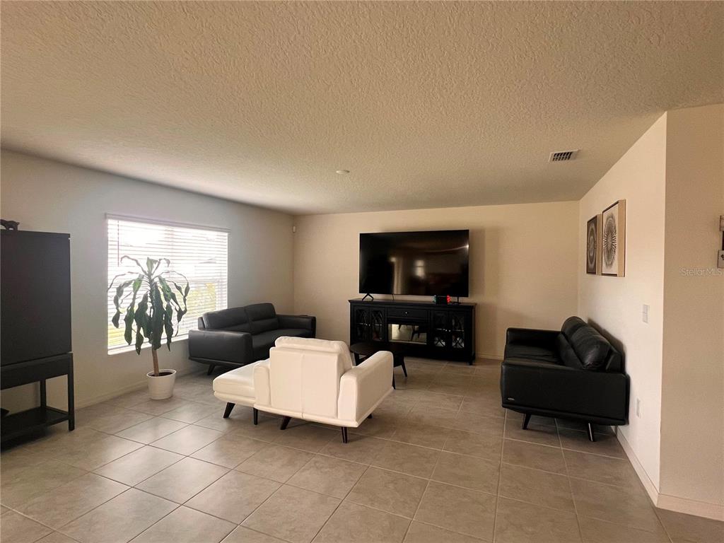 A living room features tile flooring, a large television on a console, and leather furniture — 3209 EAGLE HAMMOCK CIRCLE, KISSIMMEE, FL