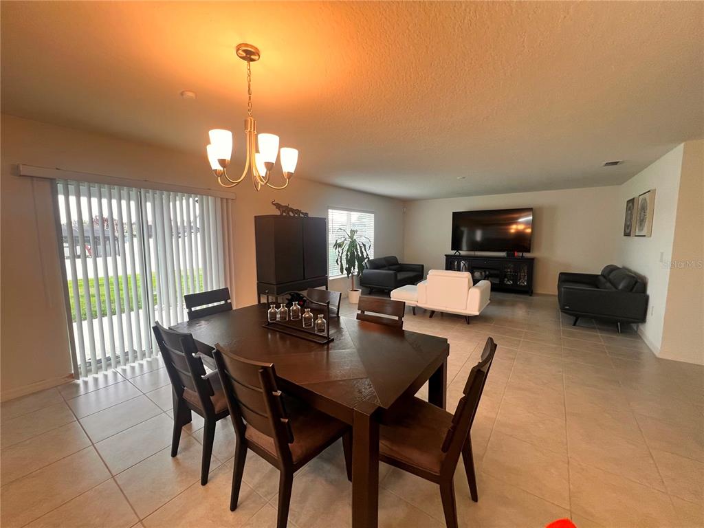 A dining area with a dark wood table opens into a living room with tile flooring — 3209 EAGLE HAMMOCK CIRCLE, KISSIMMEE, FL