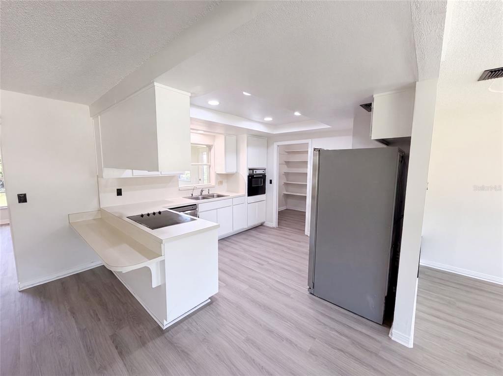 A kitchen with white cabinets, a breakfast bar, stainless steel appliances, and light wood flooring — 1148 WENTWORTH CIRCLE, ROCKLEDGE, FL