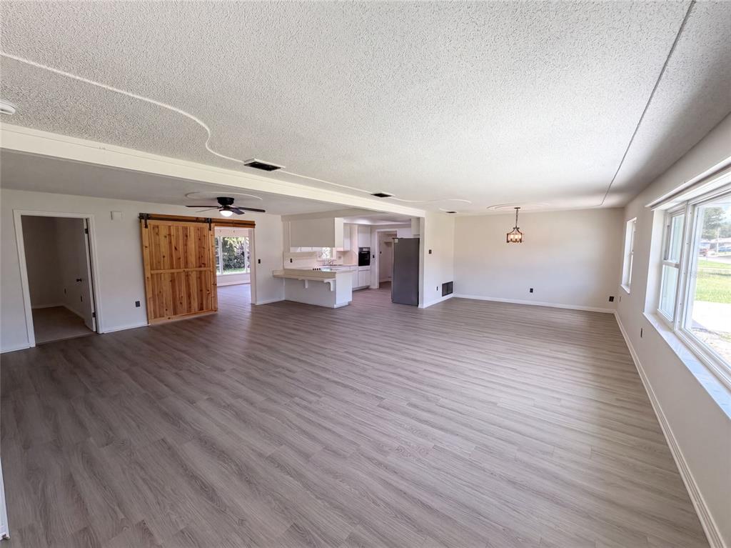 A spacious living room features light wood-look flooring, a barn door, and an open kitchen — 1148 WENTWORTH CIRCLE, ROCKLEDGE, FL