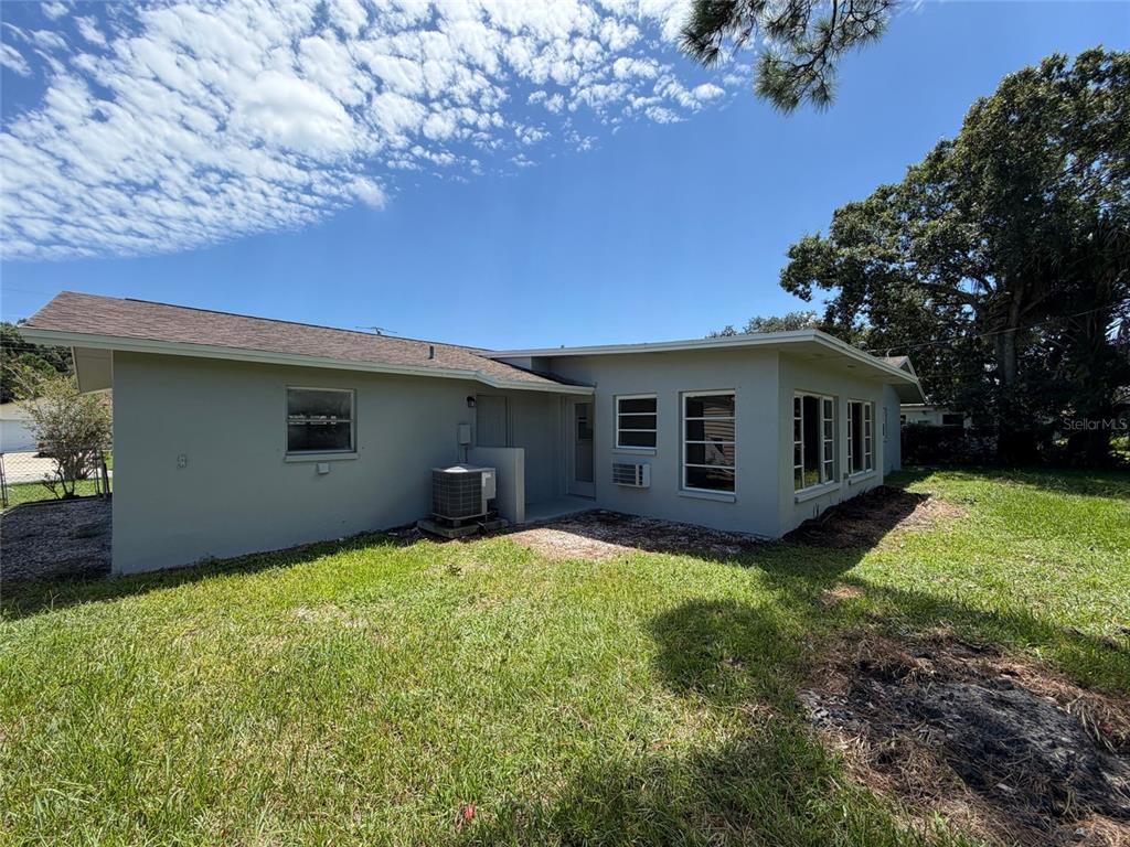 The exterior of a single-story house features a gray stucco finish and a shingled roof — 1148 WENTWORTH CIRCLE, ROCKLEDGE, FL
