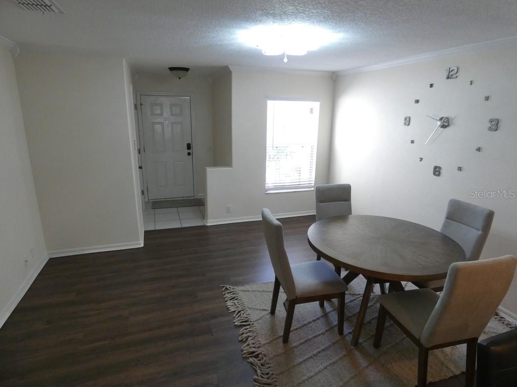A dining area features a round wooden table, four chairs, and a wall-mounted clock — 2554 SEA WIND WAY, CLEARWATER, FL