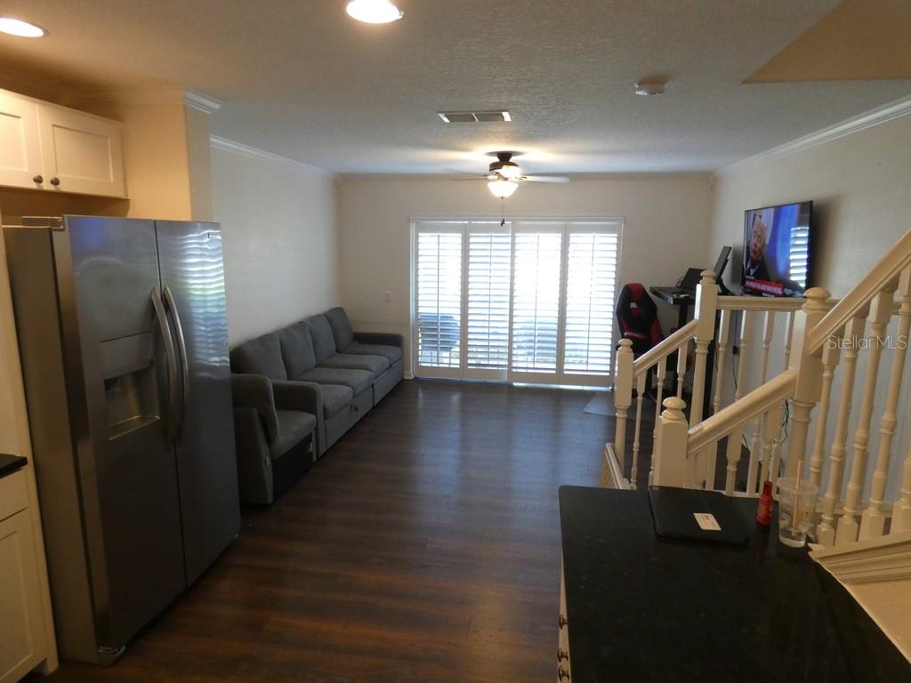 A living room with dark wood flooring, a grey sofa, and a sliding glass door — 2554 SEA WIND WAY, CLEARWATER, FL