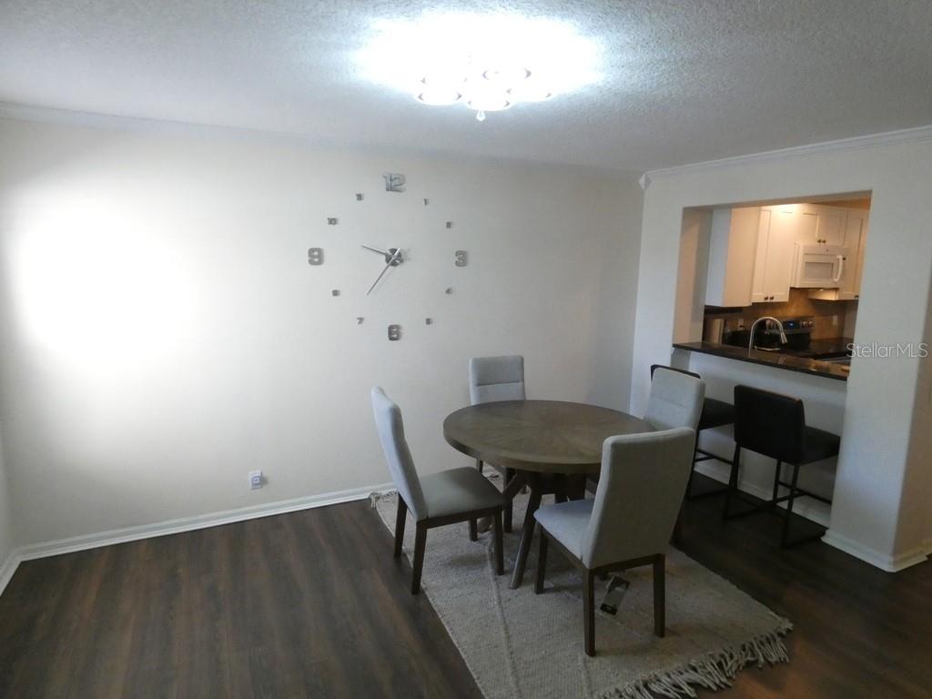 A dining area features a round wooden table, four chairs, and a large wall clock — 2554 SEA WIND WAY, CLEARWATER, FL