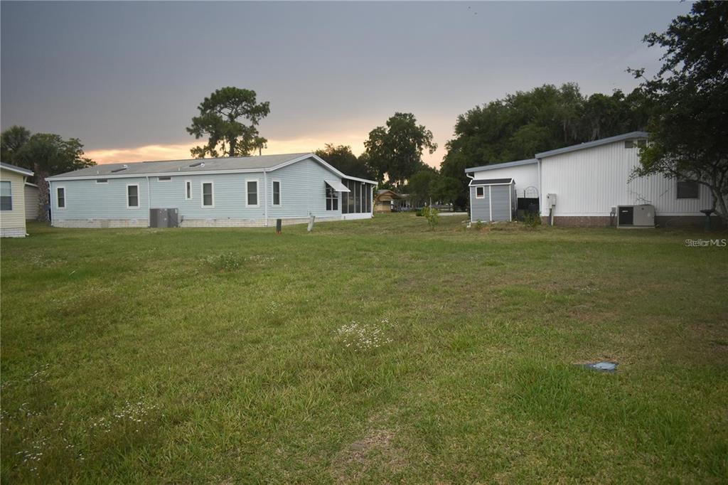 A grassy backyard view showing two manufactured homes and a small storage shed — LOT 8 BLK D LEXINGTON CIRCLE, WILDWOOD, FL