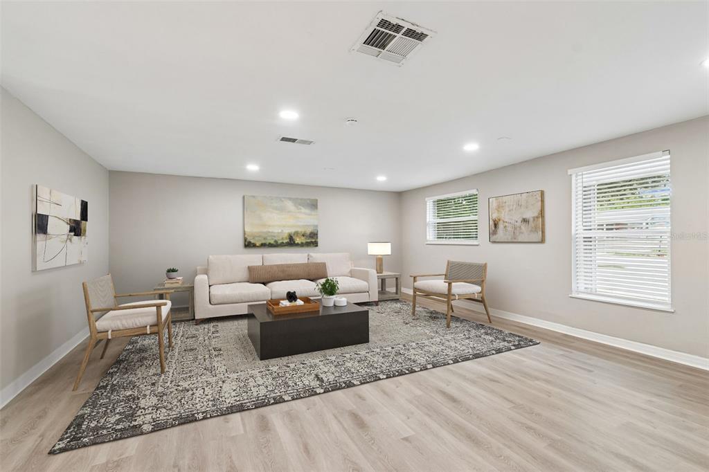 A living room features light wood-look flooring, a beige sofa, two armchairs, and a rug — 1124 JADEWOOD AVENUE, CLEARWATER, FL