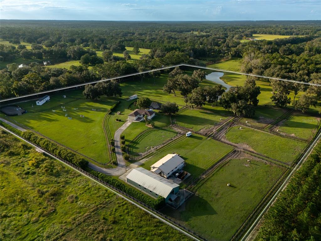 An aerial view shows a rural property with a house, a barn, and fenced pastures — 9481 W HIGHWAY 316, REDDICK, FL