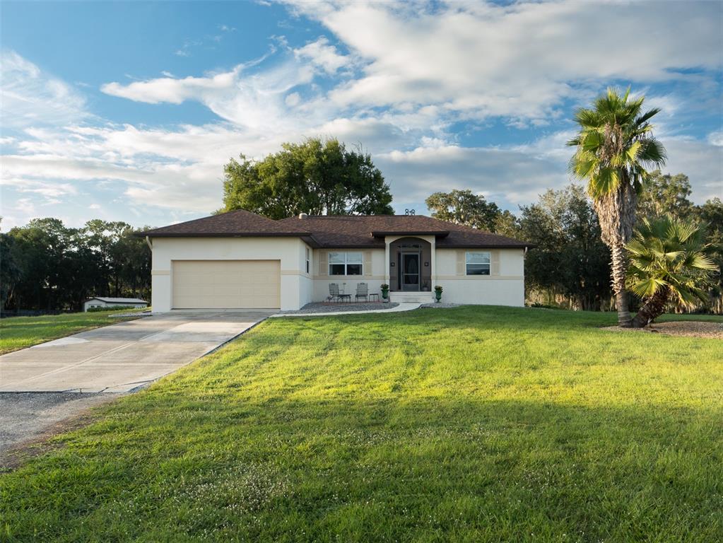 A single-story house with a beige exterior, brown roof, and attached garage sits on grass — 9481 W HIGHWAY 316, REDDICK, FL