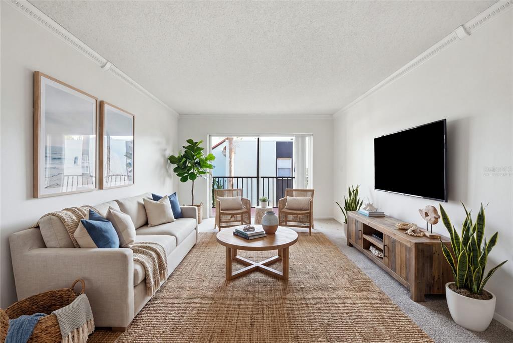 A living room features a beige sofa, a wooden coffee table, and a wall-mounted television — 3267 BENEVA ROAD UNIT 203, SARASOTA, FL
