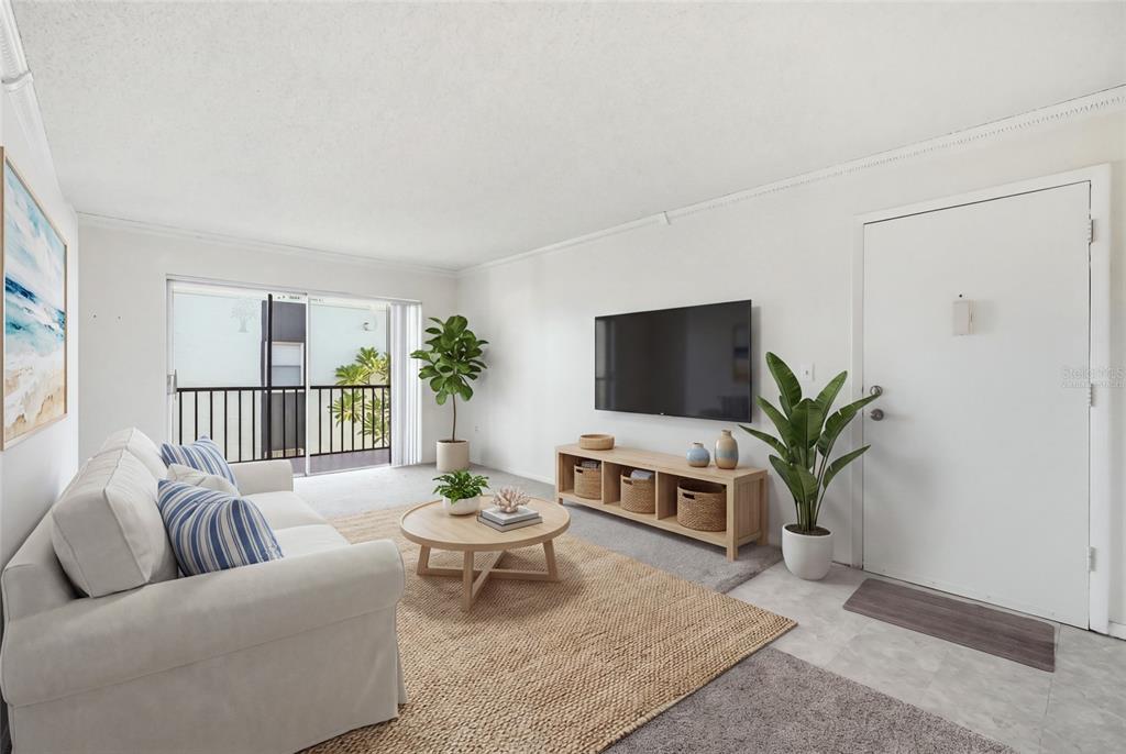 A living room features a white sofa, a television, a wooden media console, and a balcony — 3267 BENEVA ROAD UNIT 203, SARASOTA, FL