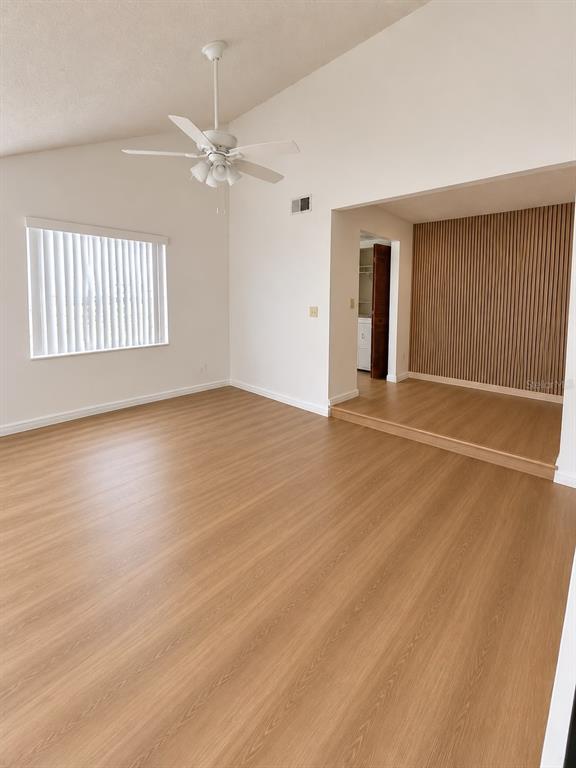 A living room with light wood-look flooring, a vaulted ceiling, and a raised dining area — 3111 RIO GRANDE TRAIL, KISSIMMEE, FL