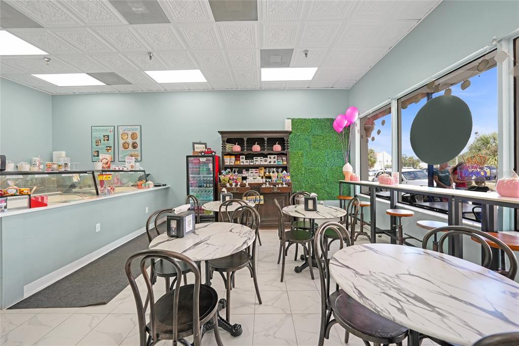 A bright cafe interior features marble-topped tables, black chairs, a service counter, and large windows — 203 W OAK STREET, ARCADIA, FL