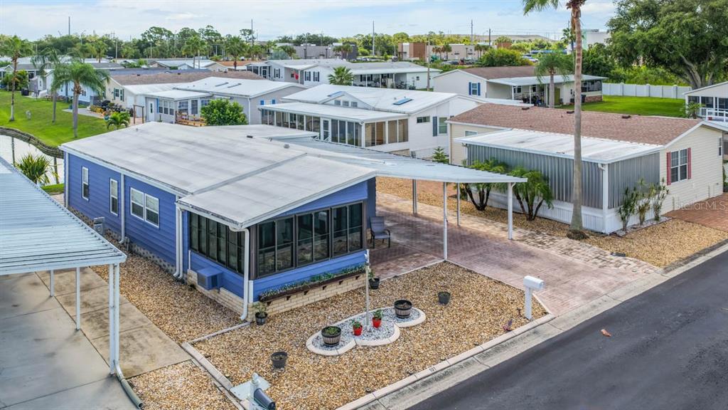 A blue single-story manufactured home features a large carport, a flag pole, and gravel landscaping — 101 SAINT GEORGE COURT, APOLLO BEACH, FL