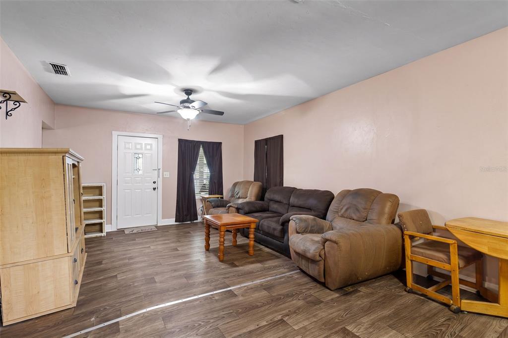 A living room features light pink walls, wood-look flooring, a ceiling fan, and brown furniture — 729 NW 3RD AVENUE, TRENTON, FL