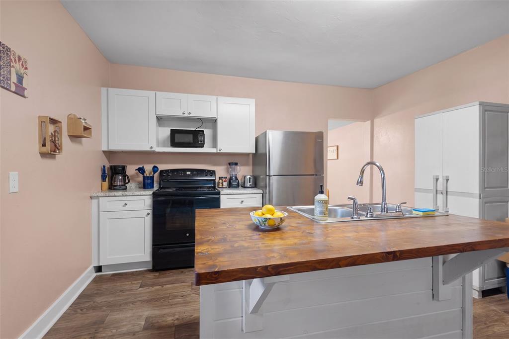 A kitchen features white cabinets, stainless steel appliances, and a wooden island countertop — 729 NW 3RD AVENUE, TRENTON, FL