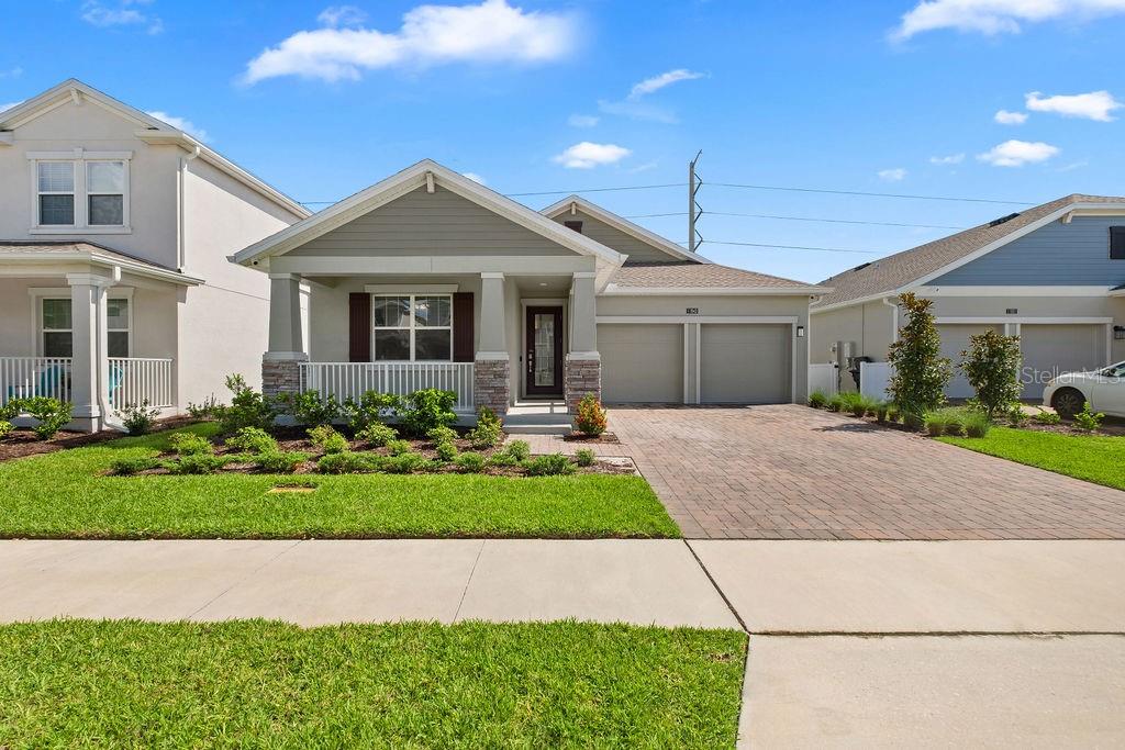 A single-story suburban house with a front porch, two-car garage, and a brick paver driveway — 11843 LANGUAGE WAY, ORLANDO, FL
