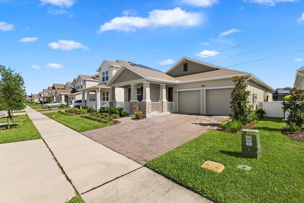 A suburban house with a brick driveway, two-car garage, and a covered front porch — 11843 LANGUAGE WAY, ORLANDO, FL
