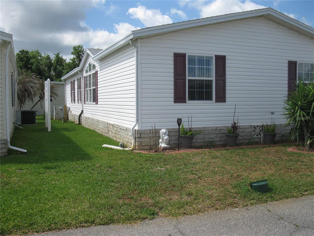 A white manufactured home with vinyl siding and a stone-patterned skirting sits on grass — 251 RAMSGATE WAY, HAINES CITY, FL