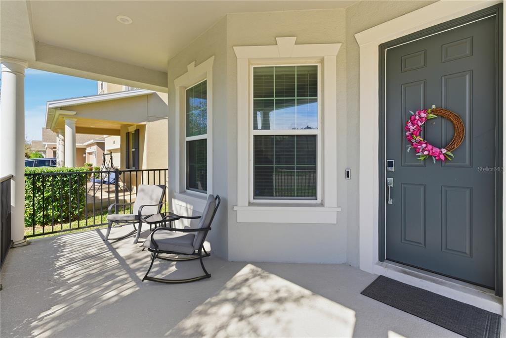 A covered front porch features two rocking chairs, a grey door, and a window — 737 PANICAL DRIVE, APOPKA, FL