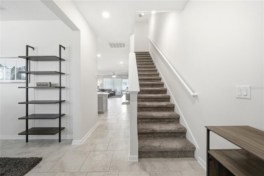 A tiled entryway features a staircase with carpeted steps and a tall black metal shelf — 737 PANICAL DRIVE, APOPKA, FL