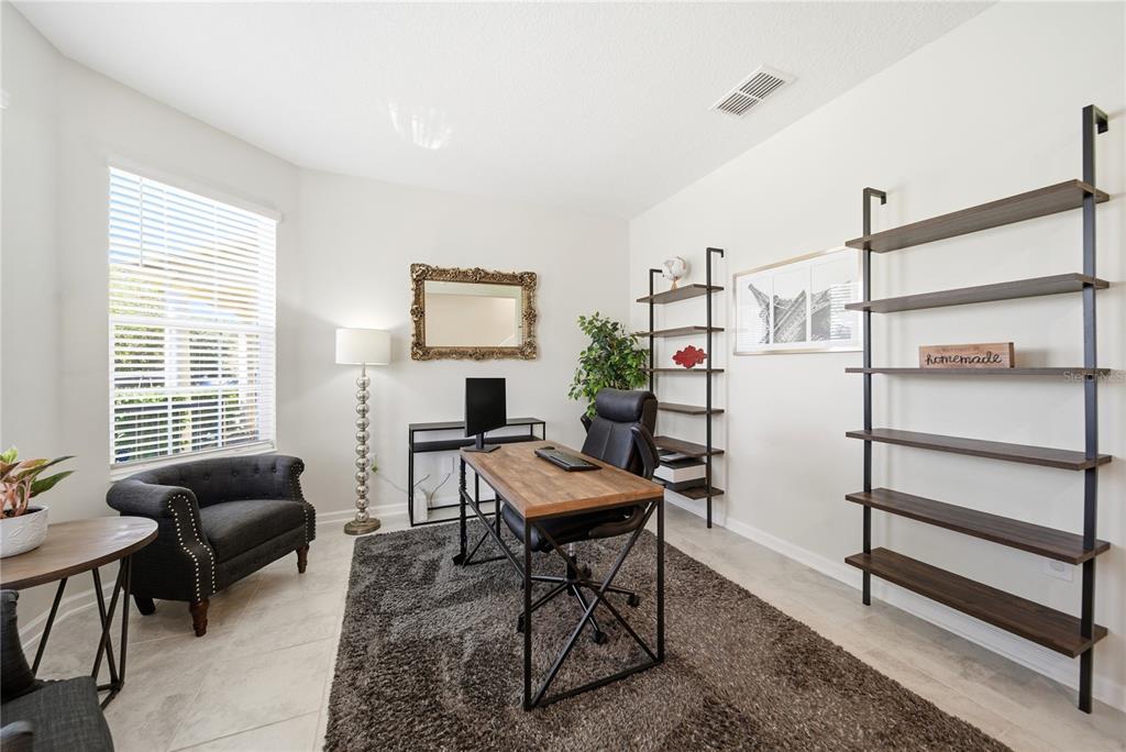 A home office features a wooden desk, two tall shelving units, and a dark armchair — 737 PANICAL DRIVE, APOPKA, FL