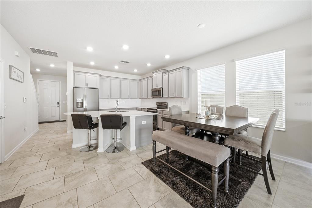 A kitchen with light gray cabinets, a central island, and an adjacent dining area — 737 PANICAL DRIVE, APOPKA, FL