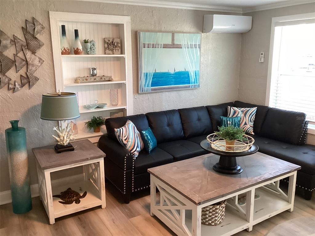 A living room features a black sectional sofa, a coffee table, and built-in shelving — 13121 4TH STREET E UNIT 1, MADEIRA BEACH, FL