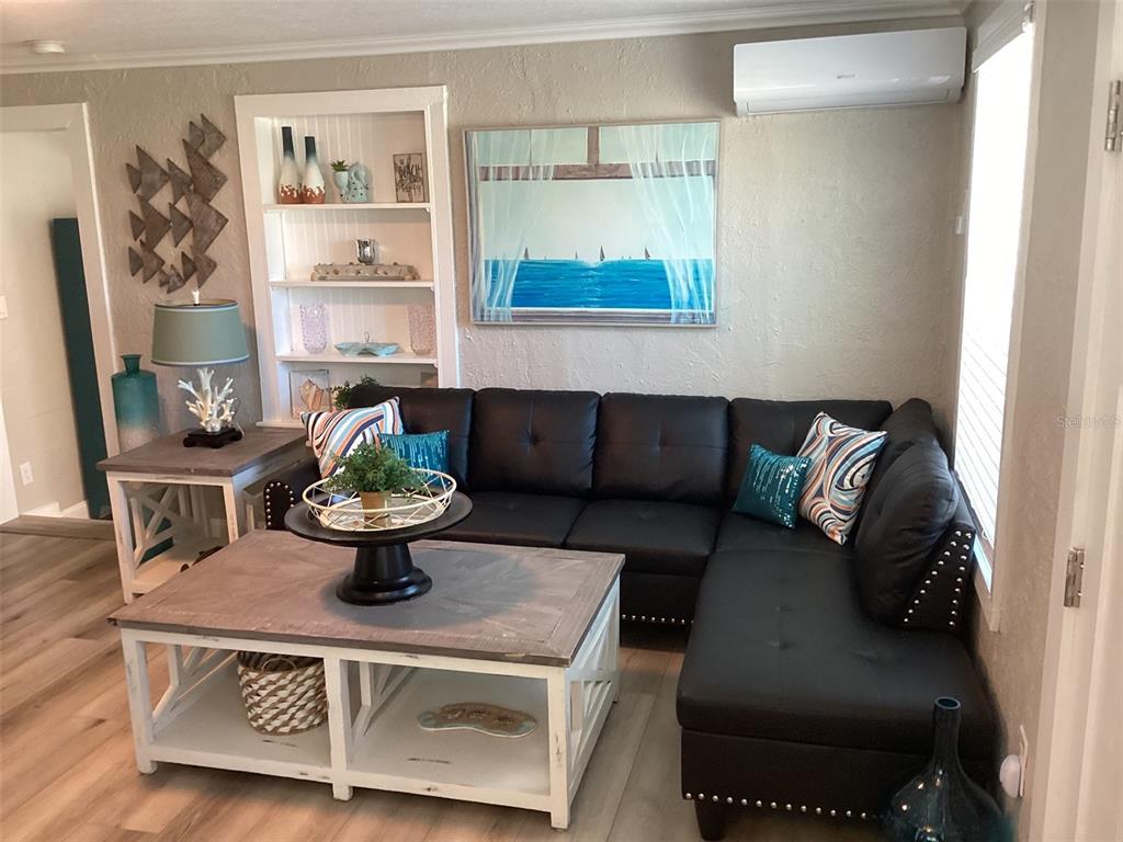 A living room features a black sectional sofa, a wooden coffee table, and built-in shelving — 13121 4TH STREET E UNIT 1, MADEIRA BEACH, FL
